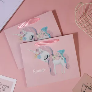 Pink cartoon unicorn paper gift bag with ribbon handle for kids party and candy packaging detail.