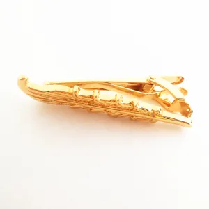 Detailaufnahme einer goldenen Krawattenklammer in Blatt-Form mit glänzender Metalloberfläche.