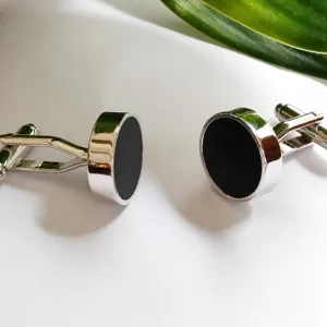 Klassieke metalen ronde manchetknopen met zwarte inleg, elegante zakelijke herenaccessoires.