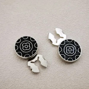 Detail shot of round black silver decorative metal buttons with classic floral pattern and clasp.
