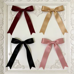 Primo piano di fiocchi in nastro di raso multicolore in bordeaux, oro, nero e rosa.