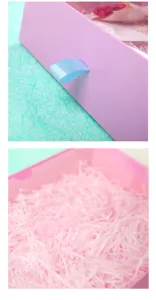 Pink gradient drawer gift box detail with blue ribbon handle and pink shredded paper inside.