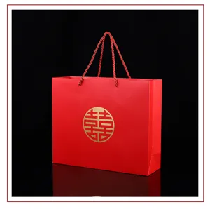 Red paper gift bag with golden double happiness symbol and woven handles, detail view.