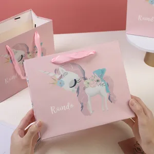 Pink unicorn paper gift bags with ribbon handles, perfect for kids birthday parties and candy packaging.