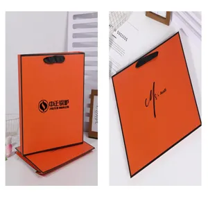 Orange paper gift bag with black border and handles, durable thick cardboard for retail shopping.