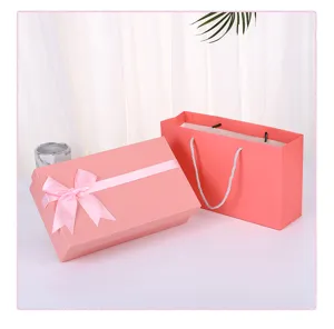 Detail shot of a pink gift box with a ribbon bow and matching paper bag for presents.