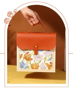 Close-up detail of the elegant leather gift box with floral pattern and orange flap handle.