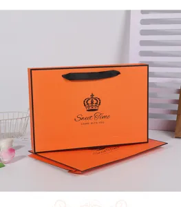 Orange paper gift bag with black ribbon handles and elegant crown print for retail packaging.