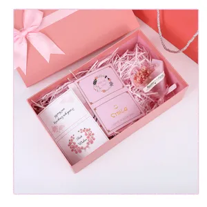 Pink bow gift box with lid, shredded paper, greeting cards and dry flower for birthday party.