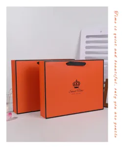 Orange paper gift bag detail view, thickened cardboard tote bag with black border and handles.