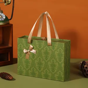 Scatola regalo vintage verde damascata con manico in nastro e fiocco, elegante confezione.