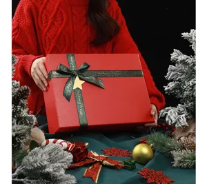 Close-up of a red Christmas gift box with green ribbon and star pendant in festive scene.