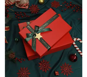 Detailed view of red Christmas gift boxes with green ribbon and gold star decor on fabric.
