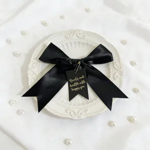 Nastro in nastro di raso nero con dettaglio etichetta stampata a oro per decorazione confezione.