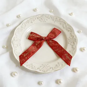 Dettaglio fiocco in nastro rosso dorato, elegante fiocco decorativo per confezioni regalo.