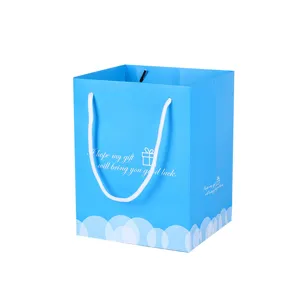 Bolsa de regalo de papel azul cielo con asas blancas y nubes para compras y detalles.