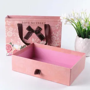 Pink drawer gift box set with matching paper bag, elegant floral print and brown ribbon bow.
