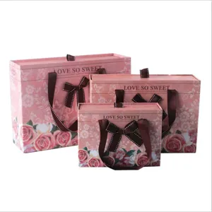 Detailed view of pink drawer gift boxes with floral prints, brown bows and carry handles.