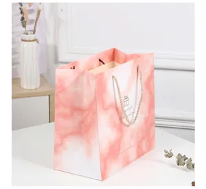 Pink marble paper gift bag with golden handles and elegant English blessing text for events.