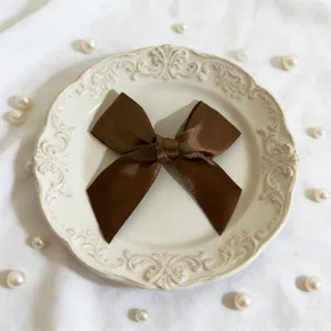 Primo piano dettagliato di un fiocco in nastro di satin marrone su piatto vintage.