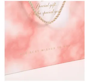 Close-up detail view of pink marble gift bag featuring gold text and elegant rope handle.