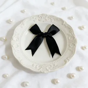Primo piano dettagliato di un fiocco in raso nero, perfetto per decorare scatole regalo.