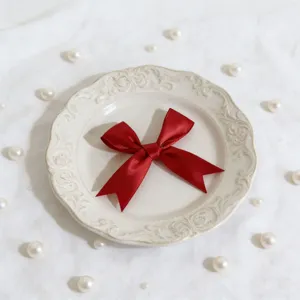 Dettaglio fiocco in nastro di raso rosso, perfetto per decorazione scatole regali.