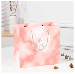 Detail view of pink marble gift bag with gold foil blessing text and woven handle.