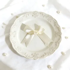 Fiocco in nastro di satin bianco crema per confezioni regalo, decorazioni, vista macro dettagliata.