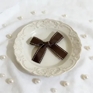 Fiocco in nastro marrone con cuciture bianche, accessorio delicato per confezioni regalo.