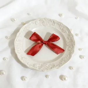 Fiocco in nastro di raso rosso con bordo dorato, ideale per scatole regalo e decoro.