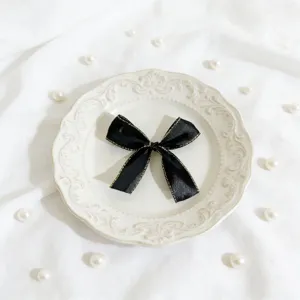 Fiocco in nastro nero con bordo dorato, ideale per decorare scatole regalo e carte.