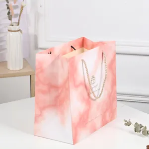 Pink marble paper gift bag with handles for wedding birthday party favors and clothing packaging.