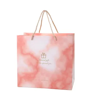 Pink paper gift bag with rope handles, elegant marble pattern for wedding and birthday gifts.