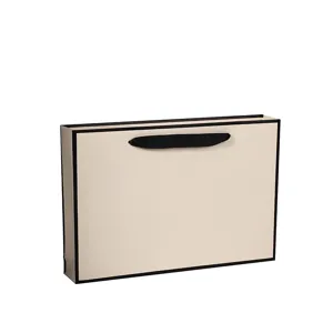 Minimalist beige paper gift bag with elegant black border and ribbon handle for retail.