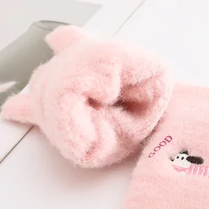 Primo piano dettagliato di guanti in maglia rosa soffice con ricamo di cucciolo e morbida trama.