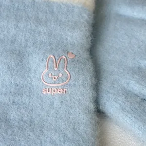 Detail view of winter plush knitted touch screen warm gloves with cute pink rabbit design.