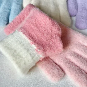 Close-up of fluffy winter knit gloves in pink and white, showing soft warm plush texture details.