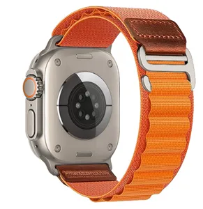 Close-up detail of the orange nylon alpine loop watch band with leather patch and metal buckle.