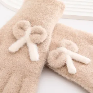 Close-up detail of winter warm fuzzy gloves with cute white bow, soft knit fabric for cold weather.