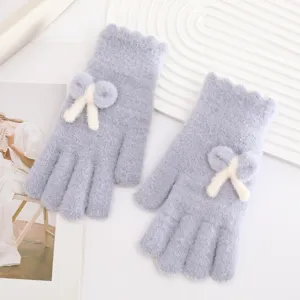 Close-up detail of fuzzy knit winter gloves with cute cream bow in light blue style.