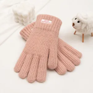 Nahaufnahme von rosa gestrickten Winterhandschuhen mit süßem Herzstickerei und Rippbündchen.