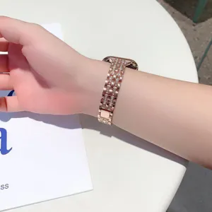Primo piano di un cinturino per orologio in metallo oro rosa con strass scintillanti al polso.