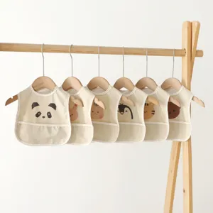 Waterproof baby bibs featuring cute cartoon animal designs hanging neatly on wooden rack.