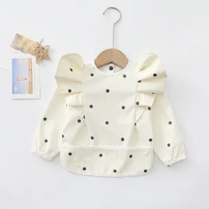 Joli bavoir imperméable à manches longues pour bébé avec ailes d'ange et pois noirs.
