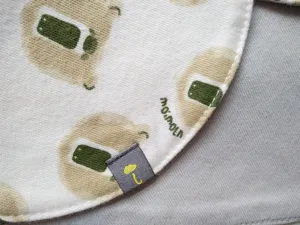 Cute baby cotton bib detail view with cartoon bear pattern and soft fabric texture.