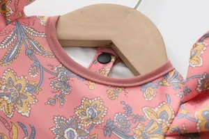 Vue détaillée du bavoir imperméable à manches longues pour enfants avec joli motif floral.