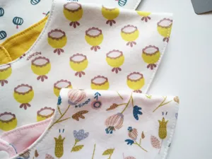 Closeup detail view of soft cotton baby triangular bib with cute floral print pattern.