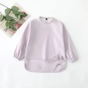 Detailed view of baby waterproof long sleeve bib with cute cat ears and front pocket.