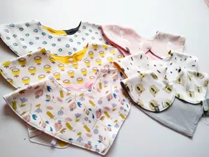 Detailed view of baby cotton bibs with cute cartoon prints, soft fabric and secure snap buttons.